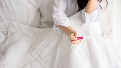 Symbolbild Frau mit einem Schwangerschaftstest / © Chompoo Suriyo (shutterstock)