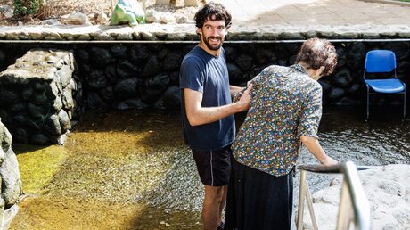 Ein Freiwilliger hilft einer behinderten Frau, die zu einer vor dem Krieg geflüchteten Gruppe Behinderter aus Kfar Rafael in Israel gehört. / © Andrea Krogmann (KNA)