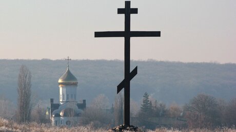 Christlich-orthodoxes Holzkreuz und Kirche in der Nähe von Kharkiv in der Ukraine / © aquatarkus (shutterstock)