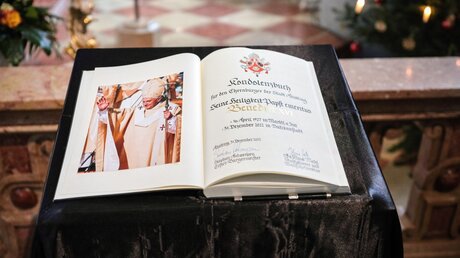 Ein Kondolenzbuch zum Gedenken an Papst Benedikt XVI. liegt auf einem Pult in der Stiftskirche Sankt Philippus und Jakobus in Altötting / © Dieter Mayr (KNA)