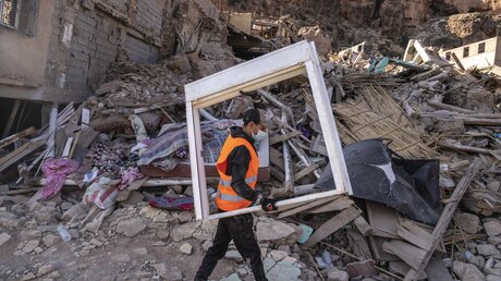 Erdbeben in Marokko: Ein Freiwilliger sammelt Möbeln aus Häusern; Während Rettungskräfte Hilfspakete aus Flugzeugen abwerfen, bemühen sich Freiwillige aus dem ganzen Land, die Not der Menschen zu lindern. / © Mosa'ab Elshamy/AP (dpa)