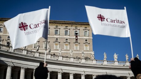 Fahnen mit dem Logo und dem Schriftzug von Caritas Internationalis am 12. Dezember 2021 auf dem Petersplatz im Vatikan. / © Cristian Gennari/Romano Siciliani (KNA)