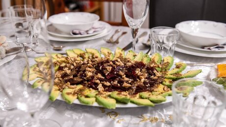 Traditionelle Speisen, darunter ein Teller mit geschnittener Avocado, auf einem gedeckten Tisch zu Rosch Haschana, dem jüdischen Neujahrsfest, am 29. September 2019 in Bonn / © Harald Oppitz (KNA)