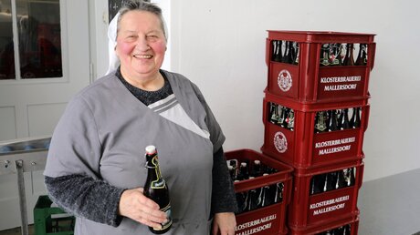 Schwester Doris Engelhard hält ein selbst gebrautes Bier in der Hand / © Julia Riese (epd)
