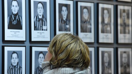 Eine Frau betrachtet Fotografien von Häftlingen im Konzentrationslager Auschwitz / © Harald Oppitz (KNA)