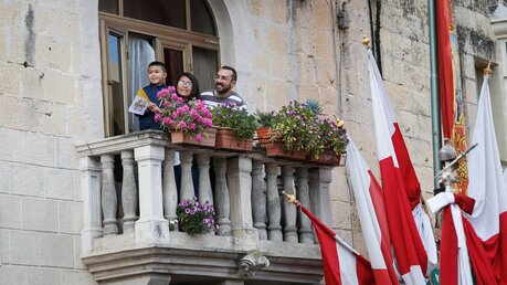 Ein Kind, eine Frau und ein Mann stehen auf einem Balkon bei einer Messe mit Papst Franziskus in Floriana (Malta) / © Paul Haring (KNA)
