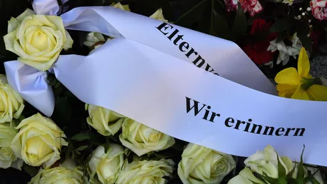 Erfurt: "Wir erinnern" steht auf einer Schleife an einem Rosenstrauß vor dem Gutenberg-Gymnasium / © Martin Schutt (dpa)