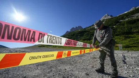 Ein Beamter der italienischen Finanzpolizei blockiert den Zugang zum Marmolada-Berg und zum Punta-Rocca-Gletscher in den italienischen Alpen mit Absperrband / © Luca Bruno (dpa)