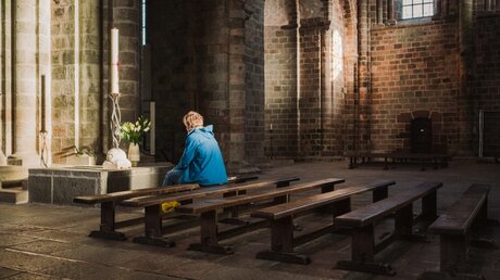Eine Frau sitzt alleine auf einer Kirchenbank / © Jean-Matthieu Gautier (KNA)