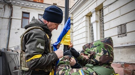 Ukrainische Freiwillige der Territorialverteidigung und ein Soldat hissen die ukrainische Nationalflagge am 7. März 2022 in Odessa (Ukraine). / © Francesca Volpi (KNA)
