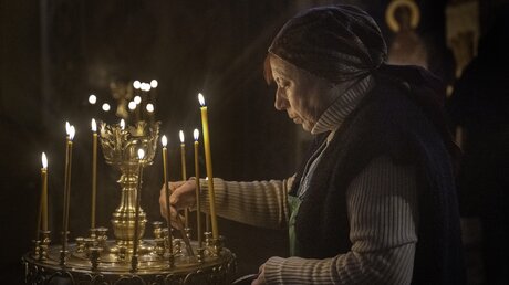 Eine Frau zündet Kerzen in der St.-Andreas-Kirche in Kiew an. / © Mark Edward Harris (dpa)