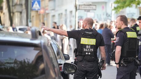 Polizisten stehen vor einer Schule in Neukölln. Zwei Schulkinder sind in einer Schule in Berlin-Neukölln vermutlich von einem Mann verletzt worden  / © Michael Kappeler (dpa)