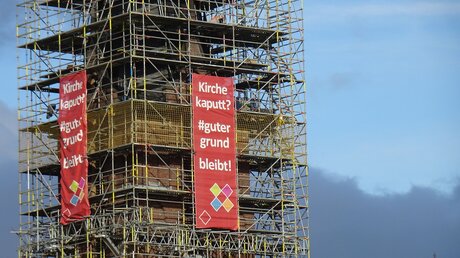 Köln-Porz: Das Plakat mit dem Slogan Kirche kaputt? #gutergrund bleibt! am eingerüsteten Kirchturm / © Kirchengemeinde Christus König Porz