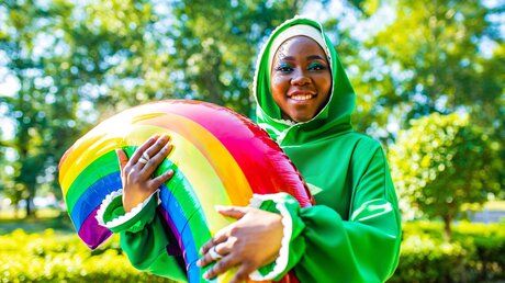 Symbolbild Eine Frau mit Kopftuch und einem Ballon in Regenbogenfarben / © yurakrasil (shutterstock)
