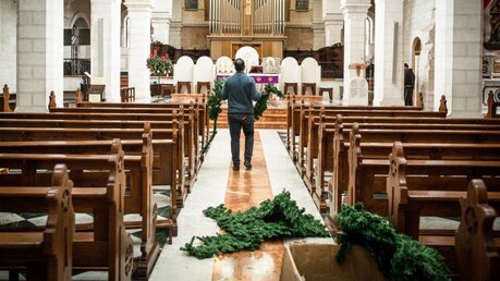 Symbolbild: Ein Mann schmückt eine Kirche mit Tannengrün / © Sebi Berens (KNA)