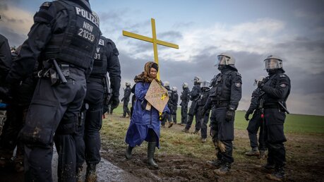 Eine Demonstrantin trägt ein gelbes Kreuz bei einer Prozession von Klimaaktivisten im Gebiet des Tagebaus Garzweiler im Erkelenzer Weiler Lützerath / © Gordon Welters (KNA)