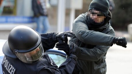 Ein gewalttätiger Demonstrant schlägt einen Polizeibeamten nieder / © Carsten Rehder (dpa)