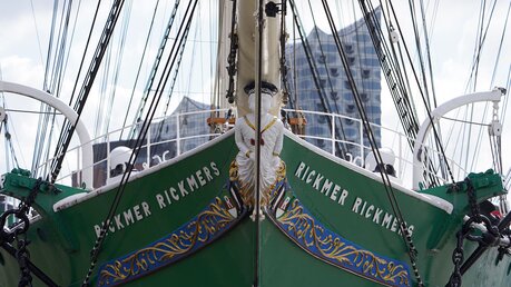 Die Galionsfigur des Museumsschiffs RICKMER RICKMERS ist im Hafen zu sehen. Im Hintergrund steht die Elbphilharmonie. / © Marcus Brandt (dpa)