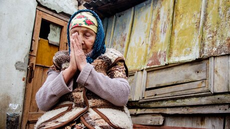 Symbolbild Eine alte Frau in der Ukraine betet / © Kharaim Pavlo (shutterstock)