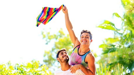 Symbolbild Homosexuelles Paar mit Regenbogenfahne / © yurakrasil (shutterstock)