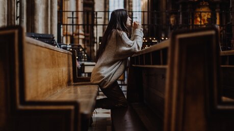 Junge Frau auf einer Kirchenbank im Gebet / © Anna Nass (shutterstock)