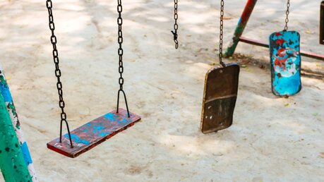 Leere und kaputte Schaukeln auf einem Kinderspielplatz / © tcareob72 (shutterstock)