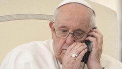 Papst Franziskus telefoniert während seiner wöchentlichen Generalaudienz auf dem Petersplatz im Vatikan.  / © Andrew Medichini (dpa)