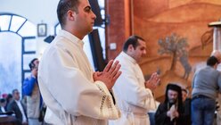 Die zwei Weihekandidaten, Yazan Fareed Bader (Vordergrund) und Michael Munther Althib, beten beim Gottesdienst zu ihrer Priesterweihe am 12. Januar 2023 in Amman, Jordanien. / © Andrea Krogmann (KNA)